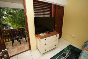 Zimmer mit einem TV auf einer Kommode und einem Balkon in der Unterkunft KC's apartment in Gros Islet