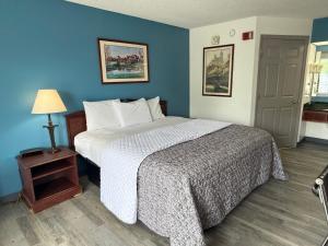 a bedroom with a large bed with a blue wall at Brentwood Inn & Suites in Roanoke Rapids