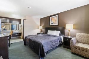 a hotel room with a bed and a chair at Economy Inn Barstow in Barstow