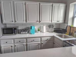 uma cozinha com armários brancos, pia e micro-ondas em Stylish & Cozy #1 8 mins to DCA & Washington DC em Alexandria mais 2 fotografias