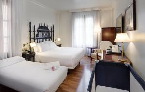 a hotel room with two beds and a desk at Sercotel Palacio de los Gamboa in Granada