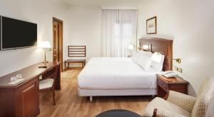 a hotel room with a bed and a desk and a television at Sercotel Palacio de los Gamboa in Granada