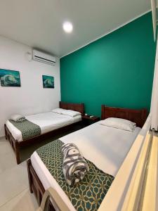 a room with two beds and a green wall at Apartahotel Caribe Diez in San Andrés