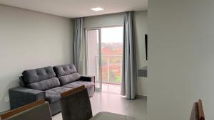 a living room with a couch and a large window at Apartamento Perto do Centro Vaga de Garagem in Foz do Iguaçu
