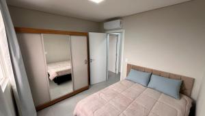 a bedroom with a bed and a mirror at Apartamento Perto do Centro Vaga de Garagem in Foz do Iguaçu