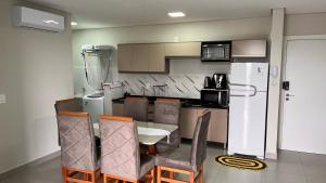 a kitchen with a table and chairs and a refrigerator at Apartamento Perto do Centro Vaga de Garagem in Foz do Iguaçu