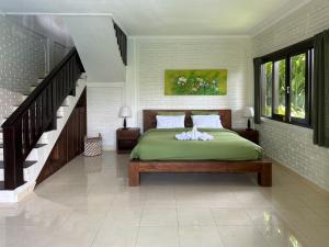 Un dormitorio con una cama verde y una escalera en Why Not Villas, en Ubud