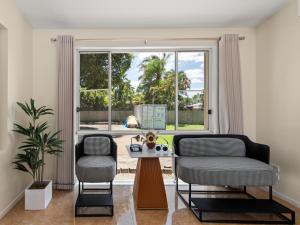ゴールドコーストにあるSpacious Waterfront Retreat in Broadbeach Watersのリビングルーム(椅子2脚、テーブル付)、窓が備わります。