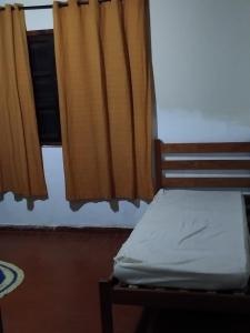 une chambre avec un lit et une fenêtre avec des rideaux dans l'établissement Casa de praia, à Itanhaém