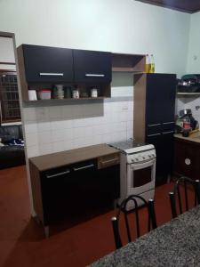une cuisine avec une cuisinière et un comptoir avec des chaises dans l'établissement Casa de praia, à Itanhaém 16 autres photos