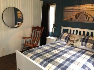 a bedroom with a bed and a chair and a mirror at Night Sky Cottage in Saint-Joachim