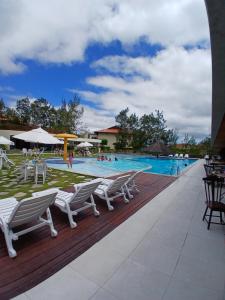 a swimming pool with chairs and people in the water at Flat Monte Castelo - Gravatá - Até 5 pessoas, próximo da área de lazer in Sairé