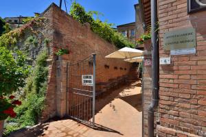 una entrada a un edificio de ladrillo con sombrilla en La Corte Medicea, en Montepulciano