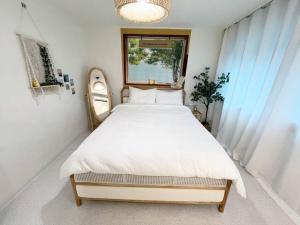 Un dormitorio con una cama grande con sábanas blancas. en Cozy 2BR Netflix Metro 5min Jamsil,Gangnam, en Seongnam