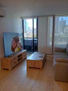 Una sala de estar con un televisor de pantalla plana y un sofá. en City views South Melbourne, en Melbourne