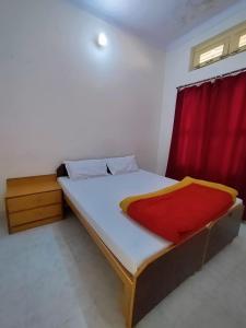 a bedroom with a bed with a red curtain at Mandakini Lodge And Restaurant in Ukhimath