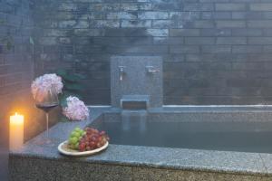 a bowl of fruit and a candle next to a bath tub at Mount Emei Heyuan Serene Residence Hot Spring Hotel in Emeishan City
