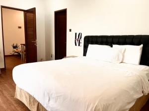 een slaapkamer met een groot wit bed met een zwart hoofdeinde bij Villa Selah in Canggu
