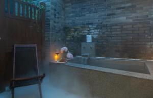 a room with a candle and a brick wall at Mount Emei Heyuan Serene Residence Hot Spring Hotel in Emeishan City