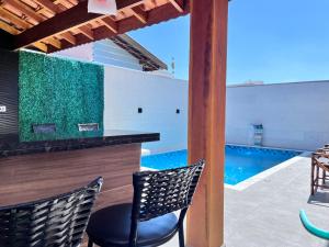 a bar with two chairs next to a swimming pool at Casa aconchegante no interior in Boituva