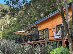 a house with a balcony with an umbrella at Vale dos Bugres Eco House- Cabana das Flores in Urubici