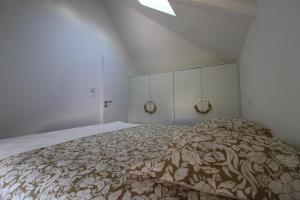 a white bedroom with a large bed with a blanket at Au petit jardin d Aizenay in Aizenay