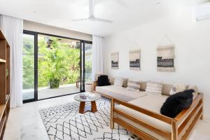 a living room with a couch and a large window at Aldea Zama - Lujo Natural en el Corazón de Tulum in Tulum