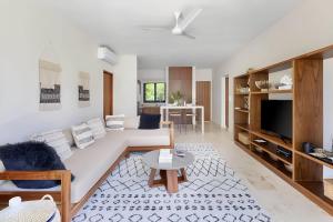 a living room with a couch and a tv at Aldea Zama - Lujo Natural en el Corazón de Tulum in Tulum