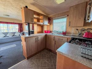 eine Küche mit Holzschränken und einer Arbeitsplatte in der Unterkunft Great 6 Berth Caravan With Side Decking In Heacham Ref 21054A in Heacham