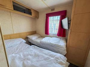 ein kleines Zimmer mit zwei Betten und einem Fenster in der Unterkunft Great 6 Berth Caravan With Side Decking In Heacham Ref 21054A in Heacham