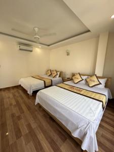 two beds in a room with wooden floors at TIẾN LUẬT in Cat Ba