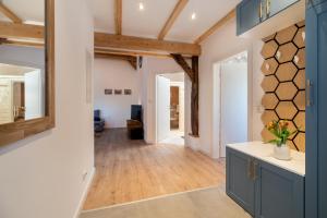 a kitchen with blue cabinets and wood floors and a hallway at FeWo zum kleinen Vogel, Sauna, Landidylle in Apen +11 photos