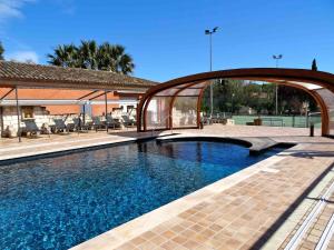 a swimming pool with an archway next to a building at L'Oliveraie de Paul in Aigues-Mortes