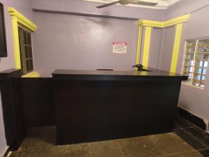 贝宁城Happyland Hotel的一张大型黑书桌,位于带两个窗户的房间