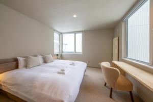 a bedroom with a bed with a chair and a window at Chihiro Niseko in Kutchan