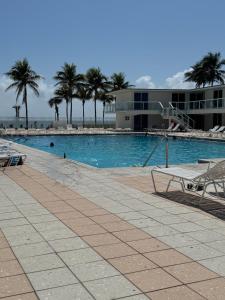 a swimming pool with palm trees and a building at Castle beach studio,tennis court and swimming pool with beach access in Miami Beach