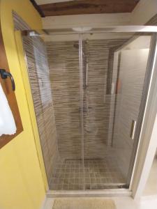 una ducha con puerta de cristal en un baño en La Casina di Mariasole, en Lajatico