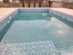 a large swimming pool with blue tiles on it at Casa De Recurso in Ghātghar