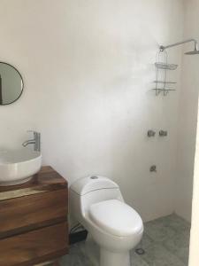 a bathroom with a white toilet and a sink at La Casa Frida in Mérida