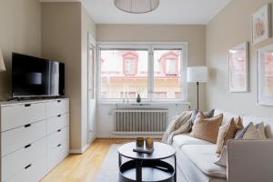 a living room with a white couch and a tv at Hotel Tre Små Rum in Stockholm