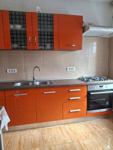a kitchen with orange cabinets and a sink and a stove at Garsoniera Luxury in Sibiu +16 photos