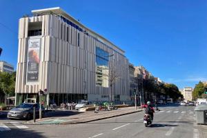 Un hombre que conduce una motocicleta por una calle al lado de un edificio. en Faculte Hotel, en Marsella