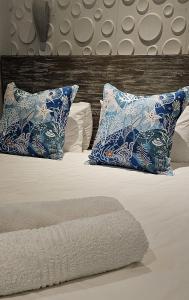 a bed with blue and white pillows on it at 10 Coral Cove Beach Lodge in Ballito +37 photos