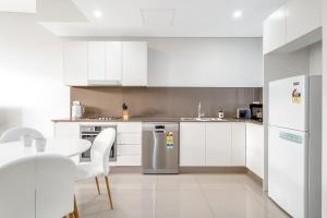 een keuken met witte apparatuur en een tafel en stoelen bij 41B Modern 1 Bedroom Abnb-Style apartment Free Parking in Bankstown