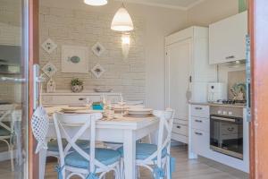 a white kitchen with a white table and chairs at Caorle Villaggio & piscina in Caorle
