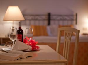 a table with a lamp and a book and wine glasses at Hotel Sylesia in Letojanni