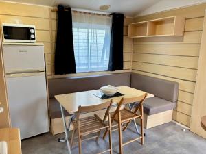 a small kitchen with a table and chairs and a refrigerator at Les jardins privés 148 Camping le Clos Cottet in Angles