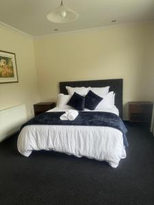 a bedroom with a large bed with black and white pillows at Ruataniwha Lodge in Twizel
