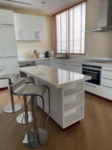 a kitchen with white cabinets and a island with bar stools at Beachfront in Ban Lum Fuang