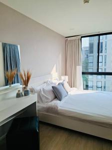 a bedroom with a large bed with a desk and a window at Modern Condo in Nimman P605 by Pimolplace in Chiang Mai